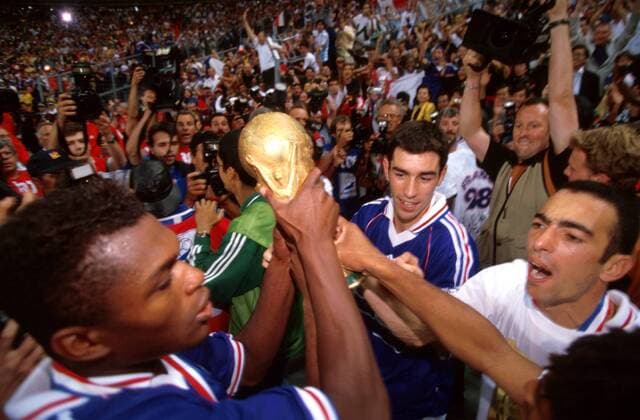 Marcel Desailly (li.), Robert Pires (Mi.) und Youri Djorkaeff (alle Frankreich) präsentieren stolz die WM-Trophäe Fußball WM Herren Weltmeisterschaft 1998, Länderspiel, Nationalmannschaft, Nationalteam, Nationaltrikot, Finalspiel Gruppe Stade de France Paris, St. Denis Freude, Begeisterung,