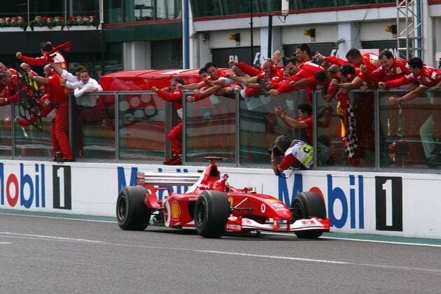 Sieger und vorzeitiger Weltmeister Michael Schumacher (Deutschland Ferrari) zieht in seinem Rennwagen an seiner jubelnden Boxencrew vorbei Motorsport Grand Prix Herren Großer Preis von Frankreich 2002, Formel 1 Weltmeisterschaft, F1, F, GP, WM Gruppe Circuit de Nevers Magny Cours Freude, Begeisterung,