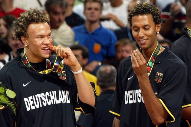 Misan Nikagbatse (li.) und Stefano Garris (beide Deutschland) testen ihre Bronzemedaillen - beißfest auch bei der Siegerehrung Basketball WM Herren Weltmeisterschaft 2002, Länderspiel, Spiel um Platz 3, Nationalmannschaft, Nationalteam Gruppe Conseco Fieldhouse Indianapolis