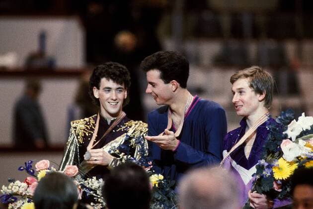 OLYMPIC LEGENDS: Brian Boitano Weltmeister Brian Boitano (Mitte, USA), Brian Orser (li., Kanada) und Alexander Fadejew (UdSSR) präsentieren stolz ihre Medaillen Eiskunstlauf WM Herren Weltmeisterschaft 1986, Eiskunstlaufen Gruppe Genf