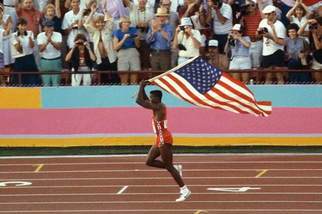 Olympiasieger Carl Lewis (USA) auf der Ehrenrunde mit der amerikanischen Flagge Leichtathletik OS Sommer Herren Olympische Spiele 1984, Sommerspiele, Olympia, Olympiade, Nationaltrikot, Einzelbild Los Angeles Freude,