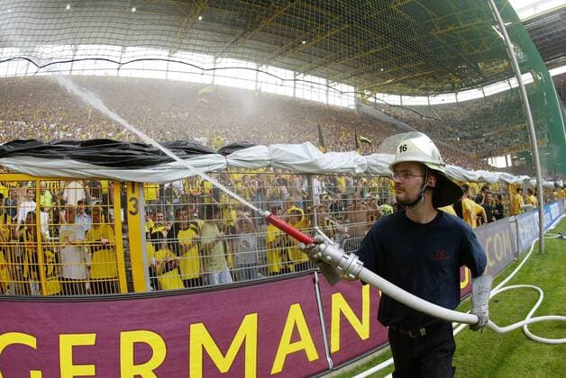 Am heißesten Bundesligaspieltag sorgt ein Feuerwehrmann mit einer ordentlichen Wasserdusche für Erfrischung unter den Dortmunder Fans Fußball 1. BL Herren Saison 2003 2004, Borussia Dortmund, BVB Totale Dortmund