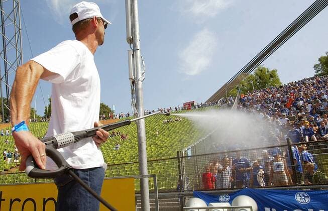 Ein Helfer sorgt mit einem Wasserstrahl für Abkühlung unter den Schalker Fans Fußball 1. BL Herren Saison 2003 2004, München - FC Schalke 04 1:1, Vdig Totale München