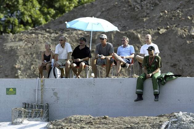 Not macht erfinderisch: Zuschauer haben es sich auf einer Mauer der Baustelle AWD-Arena mit einem Sonnenschirm gemütlich gemacht Fußball 1. BL Herren Saison 2003 2004, Hannover 96, Umbauarbeiten, Stadionumbau, Umbau, Stadionausbau, Ausbau, Vdig Gruppe AWDArena Hannover