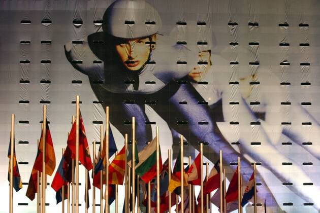 Das überdimensionale Plakat einer Eisschnelläuferin und Flaggen verschiedener Nationen werben für den olympischen Gedanken bei den Olympischen Winterspielen 2002 in Salt Lake City Biathlon OS Winter Damen Olympische Winterspiele 2002, Olympia, Olympiade, Spiele, Impressionen Totale Salt Lake City Utah