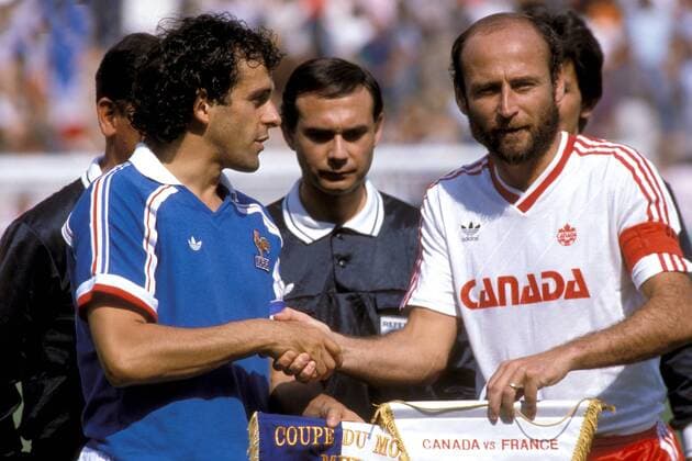 Michel Platini (li., Frankreich) und Bruce Wilson (Kanada) tauschen vor den Augen von Schiedsrichter Hernan Arce Silva (Chile) die Verbandswimpel Fußball WM Herren DEUTSCHSPRACHIGE SPORTZEITSCHRIFTEN UND -ZEITUNGEN NUR NACH RÜCKSPRACHE, Weltmeisterschaft 1986 Gruppe Kanada - Frankreich 0:1 Leon