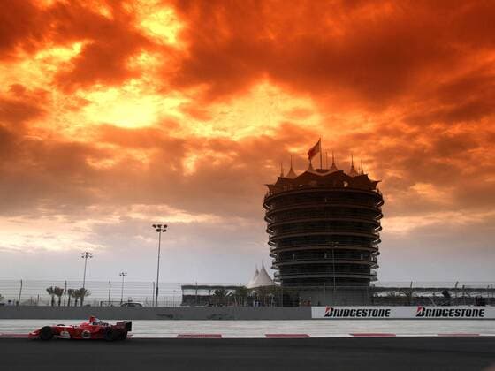 Es braut sich was zusammen über Bahrain - Michael Schumacher (Deutschland Ferrari) passiert den Vip-Tower, eingehüllt in das tiefe Orange eines beeindruckenden Sonnenuntergangs Motorsport Grand Prix Herren Großer Preis von Bahrain 2004, Formel 1 Weltmeisterschaft, F1, F, GP, WM, Vdig Totale Bahrain Racing Circuit Manama