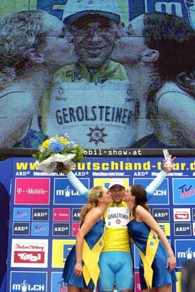 Michael Rich (Deutschland Gerolsteiner) wird im Gelben Trikot des Gesamtführenden während der Siegerehrung von zwei Hostessen geküsst, während im Hintergrund sein Bild überlebensgroß auf einer Großbildleinwand erscheint Radsport Herren Deutschlandtour 2004, Deutschlandrundfahrt, Rundfahrt, Straßenradsport, Straße, Rad, Totale 2. Etappe Bad Urach - Wangen Freude,