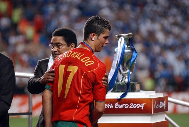 Fußball, EM Finale 2004 in Lissabon, Portugal - Griechenland 0:1 Cristiano Ronaldo (vorn) wird bei der Siegerehrung von Fußballlegende Eusebio (beide Portugal) getröstet - der Pokal ist nicht für ihn bestimmt Fußball EM Herren Euro 2004, Europameisterschaft, Länderspiel, Nationalmannschaft, Nationalteam, Finale, Endspiel Gruppe Lissabon Enttäuschung,