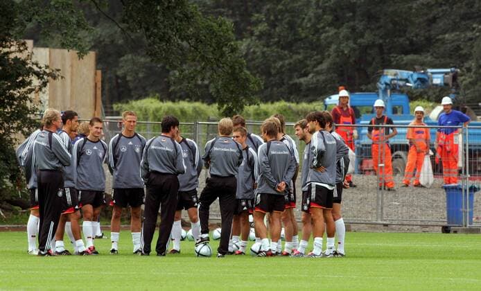 Mannschaftsbesprechung Deutschland - Bundestrainer Jürgen Klinsmann referiert im Mannschaftskreis, hinter dem Zaun schauen ein paar Bauarbeiter zu Fußball Herren Nationalmannschaft 2004, Nationalteam, Training, Vorbereitung Gruppe Frankfurt M.