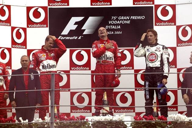 Siegerehrung nach dem GP von Italien in Monza 2004, v.li.: Michael Schumacher (Deutschland), Sieger Rubens Barrichello (Brasilien beide Ferrari) und Jenson Button (England BAR-Honda) während der Nationlahymne Motorsport Grand Prix Herren Großer Preis von Italien 2004, Formel 1 Weltmeisterschaft, F1, F, GP, WM Gruppe Autodromo Nazionale Monza Begeisterung, Freude,