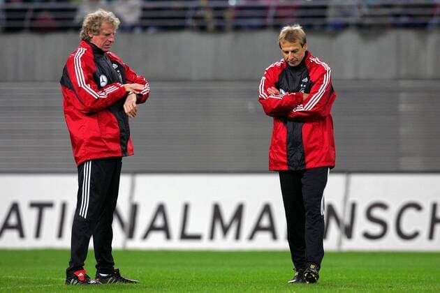 Assistent Erich Rutemöller (li.) schaut ungeduldig auf die Uhr während Bundestrainer Jürgen Klinsmann (beide Deutschland) gedankenversunken übers Feld schleicht Fußball Herren Nationalmannschaft 2004, Nationalteam, Training Gruppe Leipzig Nachdenklichkeit, Ungeduld,