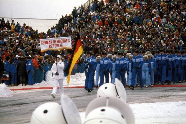 Eröffnungszeremonie der Olympischen Spiele 1980 in Lake Placid - Fahnenträger Jan Hoffmann führt die Delegation der DDR ins Stadion Eiskunstlauf OS Winter Herren Olympische Winterspiele 1980, Olympia, Olympiade, Spiele, Eröffnung, Eröffnungsfeier, Feier, Vdia Totale Einmarsch, einlaufen, auflaufen Lake Placid