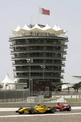 Rubens Barrichello (Brasilien Ferrari, re.) überholt vor dem VIP-Tower Testfahrer Robert Doornbos (Niederlande Jordan), während auf der Videowand der Bolide von Michael Schumacher (Deutschland Ferrari) in der Box zu sehen ist Motorsport Grand Prix Herren Großer Preis von Bahrain 2005, Formel 1 Weltmeisterschaft, F1, F, GP, WM Totale Bahrain International Circuit Manama, Sakhir, Mitzieher, Panshot