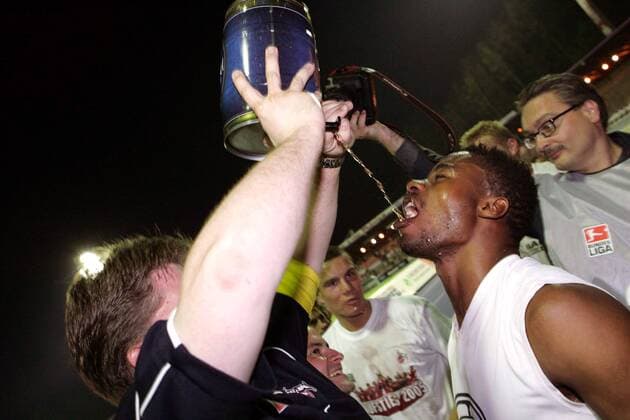 Andrew Sinkala (Köln) bekommt von Zeugwart Volker Hartjens einen ordentlichen Schluck Bier anlässlich des gerade erreichten Wiederaufstiegs Fußball 2. BL Herren Saison 2004 2005, 1. FC Köln, Aufsteiger, Aufstiegsfeier, Aufstieg, Feier, feiern Gruppe Aue, Gaffel Kölsch Freude,