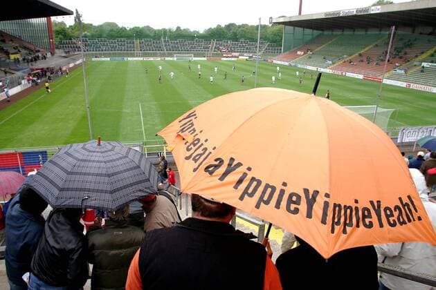 Tristesse im Uerdinger Grotenburg Stadion - schlechtes Wetter und leere Ränge, allein der farbenfrohe Regenschirm verspricht Aufmunterung: Yippie Yippie Yeah Fußball Herren Regionalliga Nord 2004 2005, 3. Liga, KFC Uerdingen 05, Vdig Totale Grotenburg Stadion Krefeld, Aufmacher Leere,