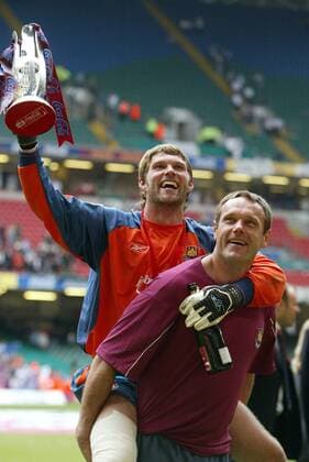 Der verletzte Torwart James Walker (West Ham) hält den Aufstiegspokal in die Luft - Dabei muss er von seinem Torwarttrainer getragen werden -  Fußball Herren Football League Championship 2004 2005, 2. Englische Liga, West Ham United, Aufstiegsfeier, Feier Gruppe Sekt, Champagner, verletzt, Verletzung Cardiff Wales Freude,