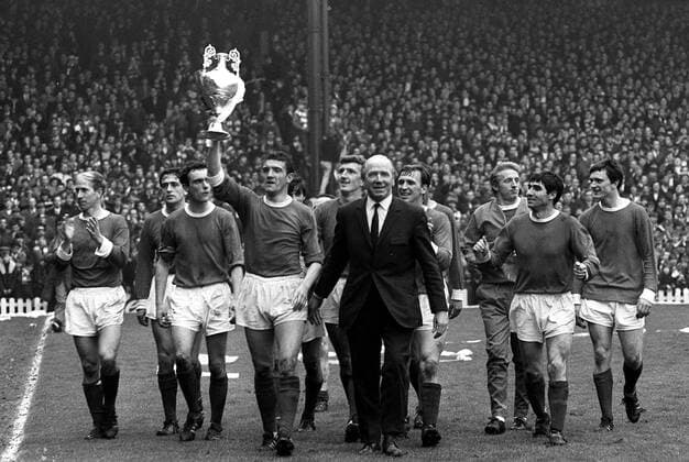 Bill Foulkes (Mitte) mit dem Meisterpokal, außerdem u.a.: Bobby Charlton (li.), John Aston (3.v.li.), Trainer Matt Busby, Dennis Law (3.v.re.), Tony Dunne (2.v.re.) und James Ryan (alle Manchester United, re.) -  Fußball Herren English First Division 1966 1967, 1. Englische Liga, Manchester United, ManU Totale Manchester Freude,