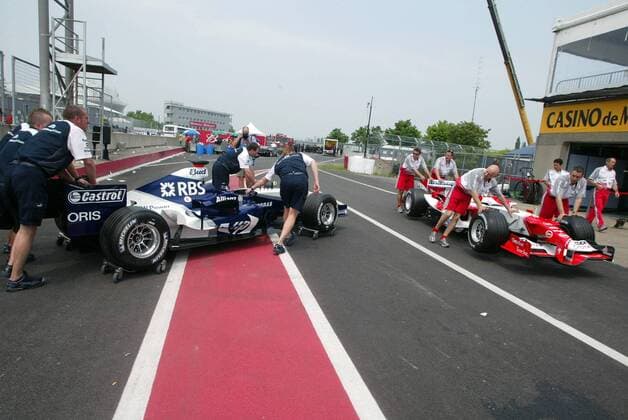Wettschieben - Mechaniker von BMW Williams (li.) und von Toyota schieben ihre Boliden über die Boxengasse und beobachten sich gegenseitig dabei sehr genau Motorsport Grand Prix Herren Großer Preis von Montreal 2005, Formel 1 Weltmeisterschaft, F1, F, GP, WM Totale Montreal