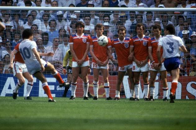 Michel Platini (li.) zieht beim Freistoß ab, Patrick Battiston (beide Frankreich, re.) läuft an - die Abwehrmauer England, v.re. mit: Bryan Robson, Trevor Francis, Ray Wilkins, Graham Rix und Paul Mariner erwartet den Ball Fußball WM Herren Weltmeisterschaft 1982, Nationalmannschaft, Nationalteam, Nationaltrikot, Länderspiel, Gruppe 4 Totale Bilbao Dynamik,