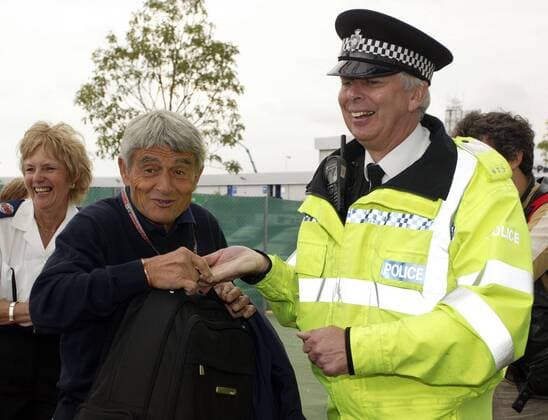 Michelin Rennleiter Pierre Dupasquier (Frankreich) muss seine Tasche von einem freundlichen englischen Polizisten genaustens untersuchen lassen, die Terroranschläge vom 7. Juli 2005 in London haben zu einer Verschärfung der Sicherheitsvorkehrungen rund... Motorsport Grand Prix Herren Großer Preis von England 2005, Formel 1 F1, F, GP, WM, Rennleitung o0 Gesellschaft Gruppe kontrollieren, Sicherheitskräfte, Aktentasche Silverstone, Chef, Reifenhersteller, lächeln Harmonie,