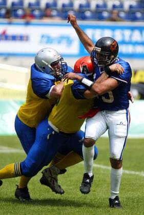 Quarterback Jean Francois Franco (Frankreich) wird von zwei schwedischen Gegenspielern getackelt American Football Länderspiel Herren World Games 2005, WorldGames, Nationalmannschaft, Nationalteam, Nationaltrikot, Länderspiel Gruppe Duisburg Dynamik, Kampf