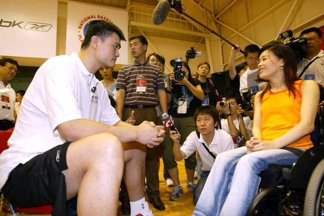 Yao Ming (China Houston Rockets) unterhält sich während des NBA Trainingscamps Basketball Without Borders mit einer Rollstuhlfahrerin und wird dabei von Journalisten umlagert -  Basketball Herren Basketball Without Borders 2005, Trainingscamp, Basketballcamp, Fernsehkamera Gruppe IMCp04988914 Beijing