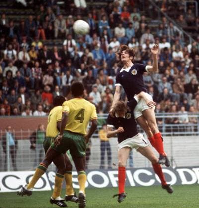 Joseph Jordan (re.) steigt zum Kopfball, daneben Denis Law (beide Schottland, 2.v.re.) und Raymond Bwanga (Zaire, 2.v.li.) - Fußball WM Herren Weltmeisterschaft 1974, Nationalmannschaft, Nationalteam, Nationaltrikot, Länderspiel, Gruppe 2 Gruppe Dortmund Dynamik, Höhe, Kampf,