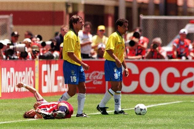 Tab Ramos (USA, li.) liegt nach dem Ellenbogencheck von Leonardo (Mitte) am Boden, daneben Zinho (beide Brasilien) -  Fußball WM Herren Weltmeisterschaft 1994, Nationalmannschaft, Nationalteam, Nationaltrikot, Länderspiel, Achtelfinale Gruppe Schmerz, Schmerzen, verletzt, Verletzung Palo Alto, Brutal,
