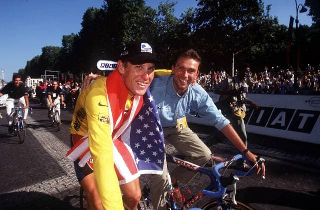 Lance Armstrong (USA, li.) feiert auf dem Champs Elysees mit seinem Sportlichen Leiter Johan Bruyneel (Belgien beide US Postal Service) und einer Nationalfahne den Gewinn der Tour de France 1999 -  Radsport Herren Tour de France 1999, Rad, Straße, Straßenradsport, Vdia Gruppe Paris Freude,