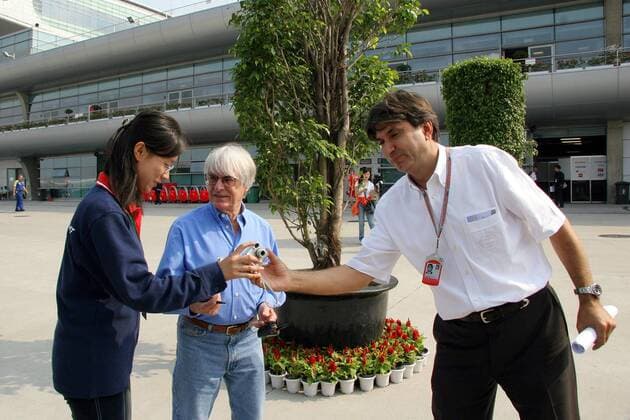 FIA Paddockdirektor Pasquale Lattuneddu (Italien, re.) gibt einem weiblichen F1 Fan ihre Kamera zurück, nachdem er so freundlich war sie mit F1 Chef Bernie Ecclestone zu fotografieren Motorsport Grand Prix Herren Großer Preis von China 2005, Formel 1 Weltmeisterschaft, F1, F, GP, WM Gruppe Shanghai