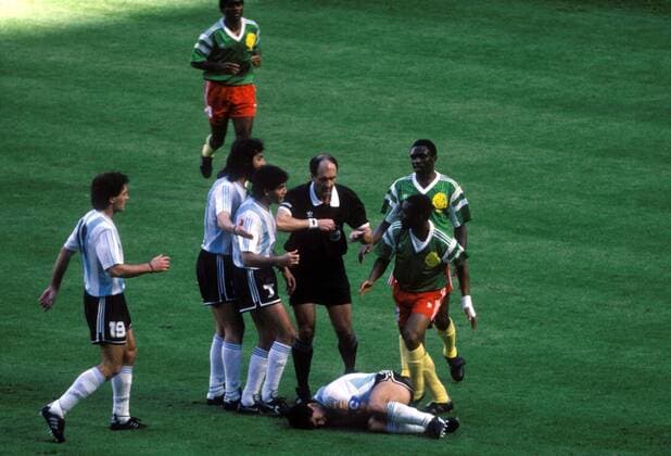 Diego Maradona (Argentinien, 3.v.re.) liegt am Boden, Schiedsrichter Michel Vautrot (Frankreich) zeigt Victor Ndip (Kamerun, 2.v.re.) die Gelbe Karte, daneben Bertin Ebwelle (Kamerun, re.) und v.li.: Oscar Ruggeri, Sergio Batista, Jorge Luis Burruchaga Fußball WM Herren Weltmeisterschaft 1990, Nationalmannschaft, Nationalteam, Nationaltrikot, Länderspiel, Gruppe B Totale Viktor, N Dip, Schmerz, Schmerzen Mailand o0 Eröffnungsspiel