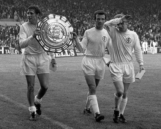 Norman Hunter (li.) und Paul Reaney (Mitte) zufrieden auf der Ehrenrunde mit dem Charity Shield, daneben Billy Bremner (alle Leeds United) -  Fußball Herren English First Division 1969 1970, One, 1. Englische Liga, Englischer Supercup, Leeds United Gruppe Leeds Glück, Freude,