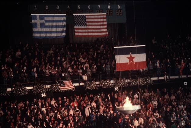 Die Nationalfahnen der USA (Mitte), Griechenlands (li.) und Jugoslawiens während der Abschlußfeier der Spiele von Lake Placid über der Olympischen Flamme OS Winter Herren Olympische Winterspiele 1980, Olympia, Olympiade, Spiele, Abschluß, Feier, Zeremonie, Vdia Totale Griechenland, Jugoslawien, Tribüne Lake Placid