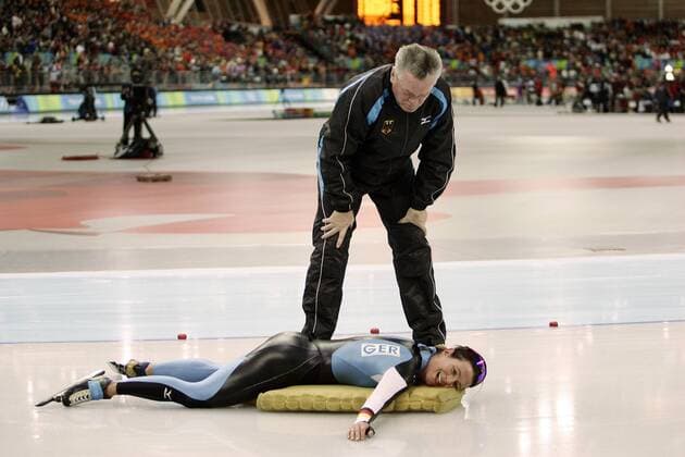 Claudia Pechstein liegt fix und fertig vor Bundestrainer Joachim Franke (beide Deutschland) auf ihrer Matte Eisschnellauf OS Winter Damen Olympische Spiele Turin 2006, Winterspiele, 5000m, 5000 m, Meter Gruppe Turin Erschöpfung,