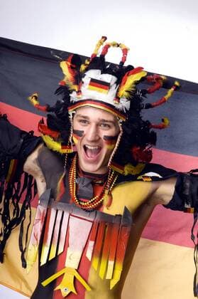 Deutscher Fußballfan mit Nationalflagge sowie Federschmuck, Bundesadler und Körperbemalung in den Nationalfarben Schwarz Rot Gold - MODEL RELEASED Fußball WM Herren Vorschau 2006, Shooting, Fotoshooting, Fototermin, Fotostudio, Studioaufnahme, Symbol o0 Aufmacher Einzelbild Gesichtsbemalung, Bemalung, bemalt, Schrei München, schreien, Jubelschrei, Freudenschrei Freude, Begeisterung,