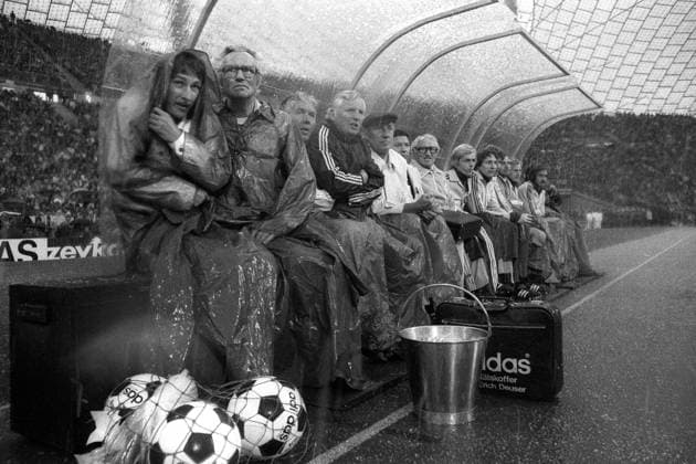 Ersatzbank BR Deutschland, v.li.: x, Betreuer Heinz Dahn, Masseur Erich Deuser, Co Trainer Jupp Derwall, Bundestrainer Helmut Schön, Mannschaftsarzt Dr. Heinrich Heß (verdeckt) schützen sich vor dem Unwetter Fußball Länderspiel Herren EM 1976, Nationalmannschaft, Viertelfinale, BRD Totale München Fußball Länderspiel Herren EM 1976, Nationalmannschaft, Viertelfinale, BRD Totale München