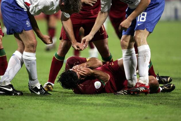 Luis Figo (Portugal, Mitte) wälzt sich verletzt auf dem Boden, Andre Ooijer (li.) und M. van Bommel (beide Niederlande) bezichtigen ihn der Schauspielerei und provozieren weiter - Fußball Länderspiel Herren WM 2006, Nationalmannschaft, Nationaltrikot, Achtelfinale, Portugal - Niederlande 1:0 Gruppe Nürnberg Fußball Länderspiel Herren WM 2006, Nationalmannschaft, Nationaltrikot, Achtelfinale, Portugal - Niederlande 1:0 Gruppe Nürnberg