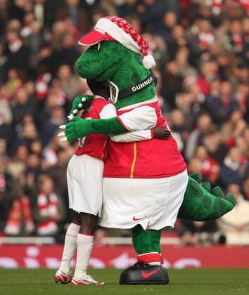 Maskottchen Gunnersaurus umarmt Emmanuel Eboue (beide Arsenal) -  Fußball Herren English Premier League 2007 2008, 1. Englische Liga, Arsenal FC London Gruppe London Harmonie, Fußball Herren English Premier League 2007 2008, 1. Englische Liga, Arsenal FC London Gruppe London Harmonie,