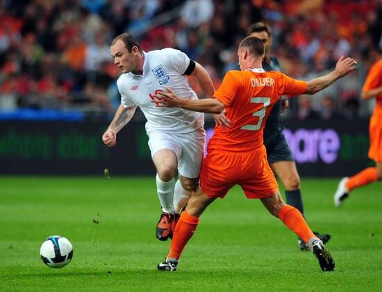 Wayne Rooney (L) of England and Andre Ooijer of Holland EDITORIAL USE ONLY. No use with unauthorised audio, video, data, fixture lists, club league logos or live services. Online in-match use limited to 120 images, no video emulation. No use in betting, games or single club league player publications.