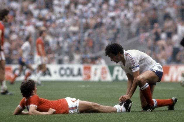 Michel Platini (Frankreich) hilft einem unter Krämpfen leidenden Gegner Fußball WM Herren WM 1982, Länderspiel, Nationalteam, Nationaltrikot, England - Frankreich 3:1 Gruppe Bilbao