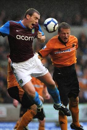 Richard Dunne of Aston Villa (L) clears under pressure from Chistophe Berra of Wolverhampton Wanderers EDITORIAL USE ONLY. No use with unauthorised audio, video, data, fixture lists, club league logos or live services. Online in-match use limited to 120 images, no video emulation. No use in betting, games or single club league player publications.
