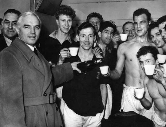 Fußball, Trainerhistorie, Leeds United Coach RAICH CARTER (L) POURS JOHN CHARLES A SPOT OF CHAMPAGNE IN CELEBRATION OF THEIR WIN OVER HULL TO CLINCH PROMOTION TO DIVISION ONE . JACK CHARLTON IN BACKGROUND. HULL CITY v LEEDS UNITED, 28 4 56.  o0 Aufstieg Aufsteiger Jubel Freude Second Division Aufmacher kurios Komik Alkohol