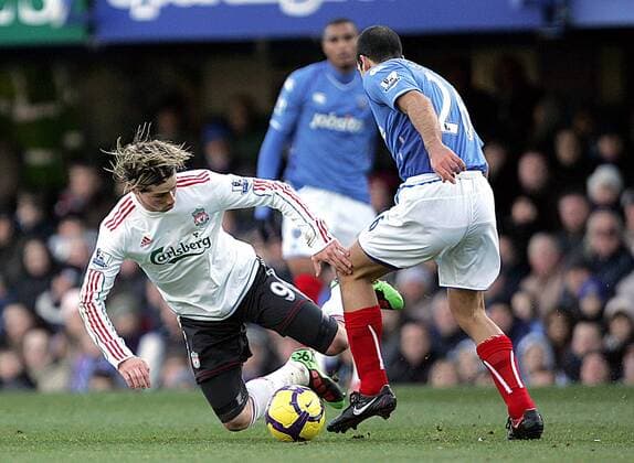 Fernando Torres (L) of Liverpool FC goes to ground following a tackle from Tal Ben Haim of Portsmouth Barclays Premier League Portsmouth v Liverpool 19th December, 2009 EDITORIAL USE ONLY. No use with unauthorised audio, video, data, fixture lists, club league logos or live services. Online in-match use limited to 120 images, no video emulation. No use in betting, games or single club league player publications.