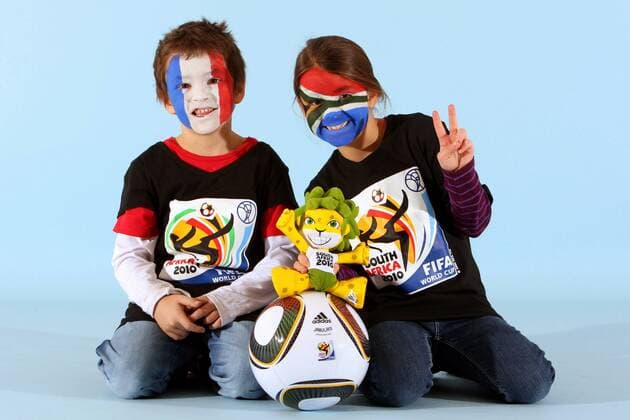 Kinder mit Gesichtsbemalung der WM Teilnehmer Frankreich (li.) und Südafrika, Gruppengegner in der Gruppe A, mit WM Maskottchen Zakumi und Adidas Ball Jabulani - Fotoshooting mit Kindern - MODEL RELEASED -  o0 Objekte