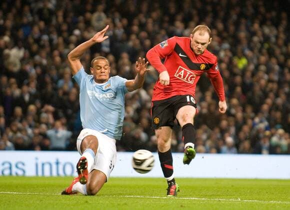 Vincent Kompany of Manchester City blocks a shot by Wayne Rooney of Manchester United Carling Cup Semi Final 1st Leg - Manchester City (blue) vs Manchester United (red) - 19th January, 2010 EDITORIAL USE ONLY. No use with unauthorised audio, video, data, fixture lists, club league logos or live services. Online in-match use limited to 120 images, no video emulation. No use in betting, games or single club league player publications.