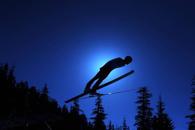 Skispringer im Gegenlicht, Skisspringen, Skisprung, Ski Jumping, Mannschaft, Team, 22.02.2010. XXI. Olympische Winterspiele 2010 in Vancouver Kanada. o00 Flugphase Wald Symbol