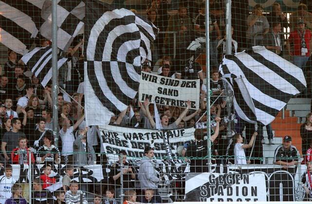 Fußball, Stadiongeschichte Wacker Burghausen Saison 2009 2010, Fussball 3.Liga, SV Wacker Burghausen, Burghausener Fans schwenken Fahnen o0 Fan, Fußballfan, Publikum, Fanblock, Fahne, Fanfahne, totale