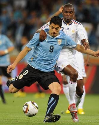 Uruguay s Luis Suarez (L) shoots beside French Eric Abidal during a Group match of the 2010 FIFA World Cup in Cape Town, on June 11, 2010. The match ended with a 0-0 draw. - France (white) vs Uruguay - 