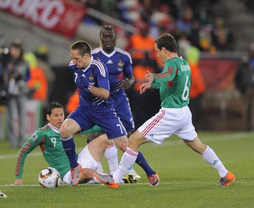Franck Ribery of France skips through tackles by Gerardo Torrado (R) and Guillermo Franco of Mexico --- FIFA World Cup 2010 - France (blue) vs Mexico (green) 0:2 --- EDITORIAL USE ONLY. No use with unauthorised audio, video, data, fixture lists, club league logos or live services. Online in-match use limited to 120 images, no video emulation. No use in betting, games or single club league player publications.
